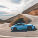 A blue 2023 Porsche 911 Carrera T navigates a switchback corner.